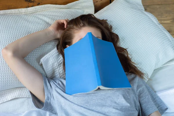 Jeune femme dormir sur le lit avec livre — Photo