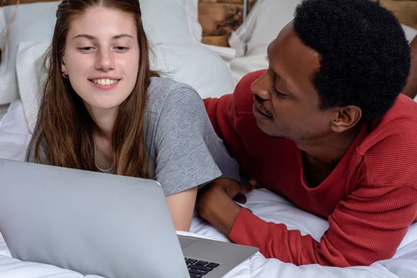 Giovane coppia utilizzando il computer portatile in un letto a casa . — Foto Stock