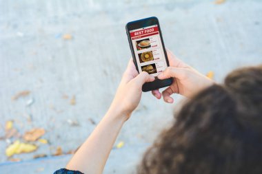 Akıllı telefonlu bir kadın yemek siparişi veriyor.