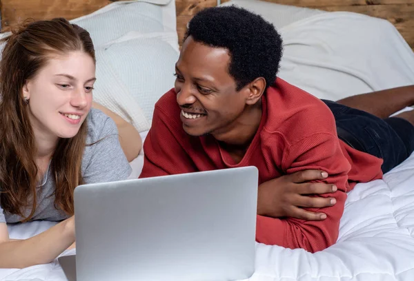 Evde bir yatakta laptop kullanarak genç çift. — Stok fotoğraf