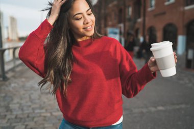 Elinde kahve tutan genç bir kadın..