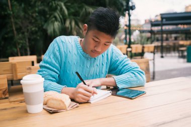 Asyalı bir adam kahvecide okuyor..