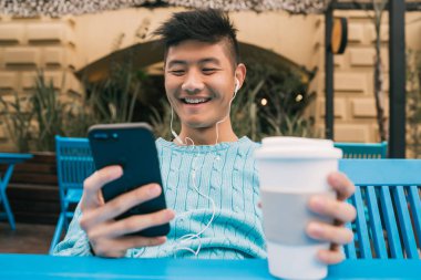 Asyalı adam cep telefonunu kullanıyor..