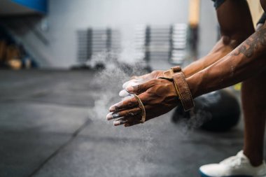 Fitness adamı tebeşir magnezyum tozuyla ellerini ovuşturuyor..