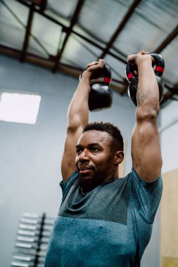 Atletik adam Crossfit kettlebel ile egzersiz yapıyor..