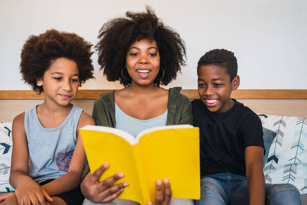 Afro mother reading a book to her children.