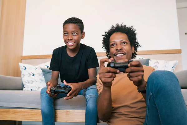 Father and son playing video games together at home.