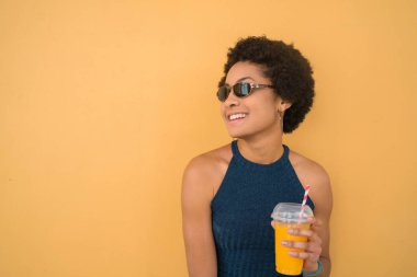 Genç afro kadın taze meyve suyu içiyor..