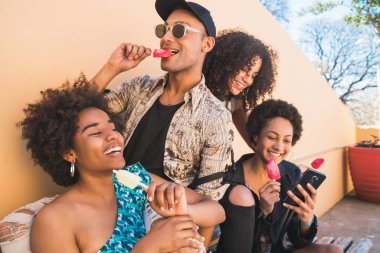 Çok ırklı arkadaş grubu yemek yerken tatilin tadını çıkarıyor.