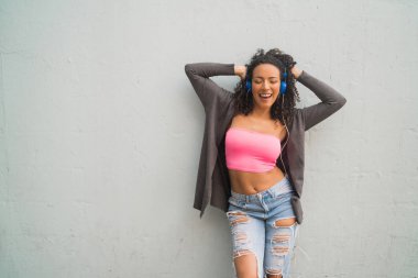 Genç Afro kadın kulaklıkla müzik dinliyor..