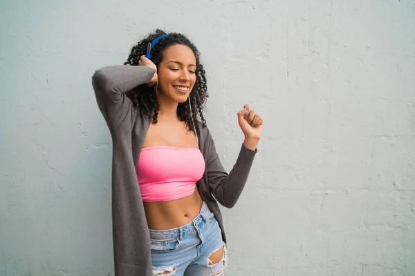 Mladá afro žena poslouchá hudbu se sluchátky. — Stock fotografie