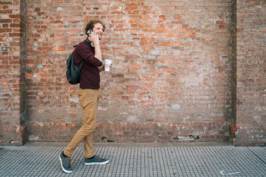 Genç adam dışarıda telefonla konuşuyor..