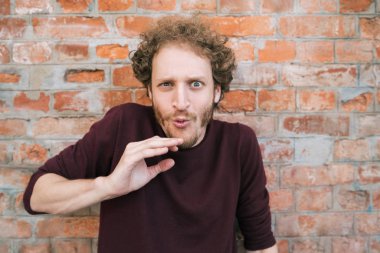 Genç adam tuğla duvara yaslandı..