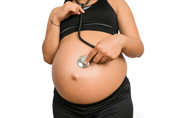 Schwangere mit Stethoskop am Bauch hört dem Baby zu.. — Stockfoto