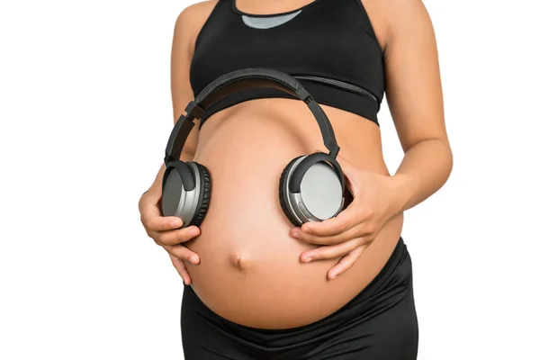 Mulher grávida segurando fones de ouvido na barriga. — Fotografia de Stock