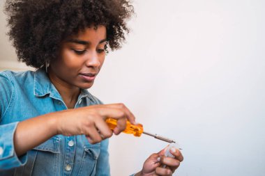 Afro kadın tornavidayla bir şey tamir ediyor..