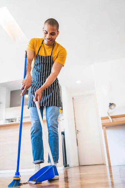 Lateinischer Mann kehrt zu Hause mit Besen den Holzboden. — Stockfoto