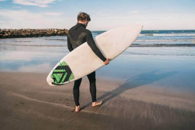 Sörfçü sörf tahtasıyla suya giriyor..