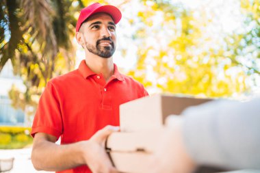 Eve teslimat yaparken paket taşıyan teslimatçı..