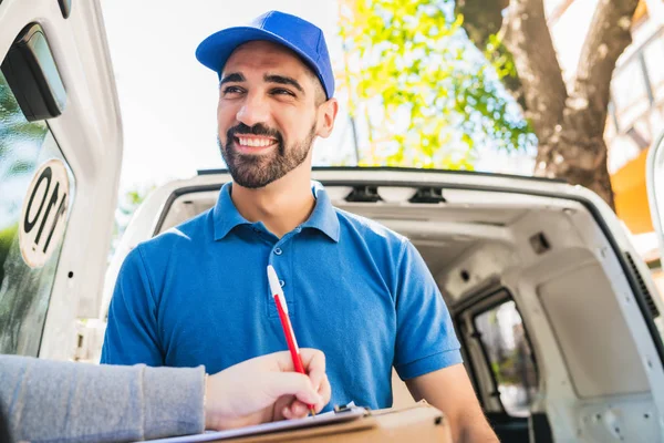 Leveringsman met pakket terwijl de klant zich aanmeldt klembord. — Stockfoto