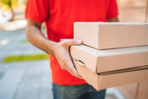 Entrega hombre llevando paquetes mientras que hace entrega a domicilio. — Foto de Stock