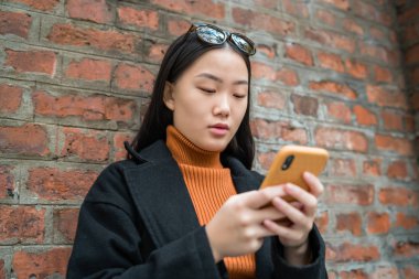 Cep telefonunu kullanan Asyalı kadın..