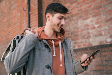 Genç adam sokakta cep telefonunu kullanıyor..