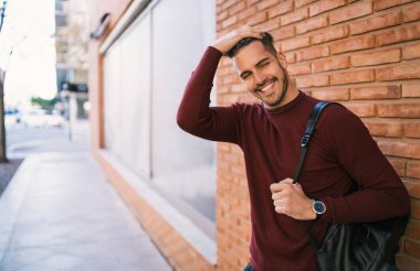 Genç adam tuğla duvara yaslandı..