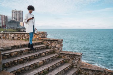 Cep telefonunu kullanan genç bir kadın..