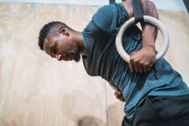 Atletik adam yüzüklerle kaslarını geliştiriyor..