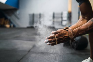 Fitness adamı tebeşir magnezyum tozuyla ellerini ovuşturuyor..