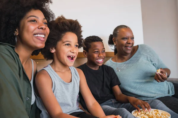 Grand-mère, mère et enfants regardant un film à la maison. — Photo