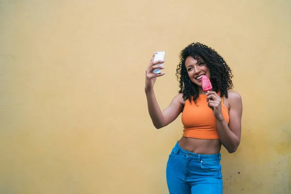 Afro mujer tomando selfies con teléfono mientras come helado. —  Fotos de Stock