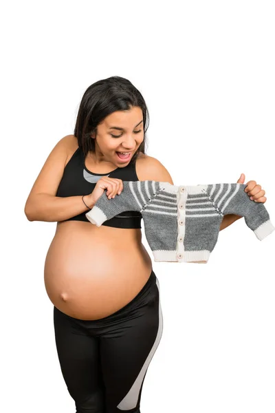 Mulher grávida segurando roupas de bebê . — Fotografia de Stock