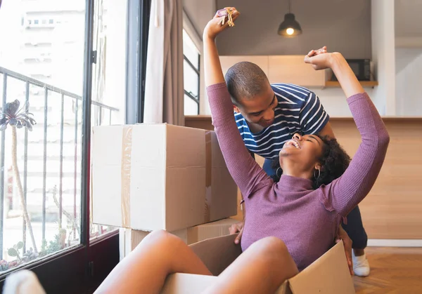 Pareja latina divirtiéndose con cajas de cartón en casa nueva. —  Fotos de Stock