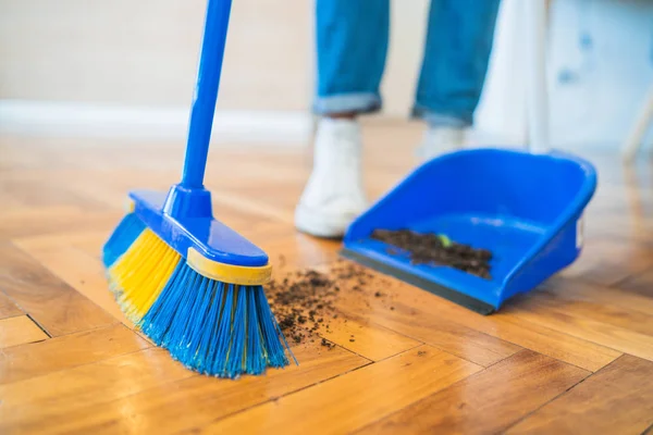 Hombre latino barriendo piso de madera con escoba en casa . — Foto de Stock