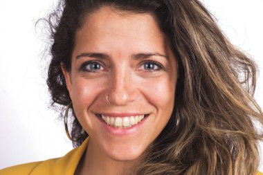 Genç ve güzel bir kadının portresi kameraya bakıyor ve beyaz arka planda gülümsüyor..