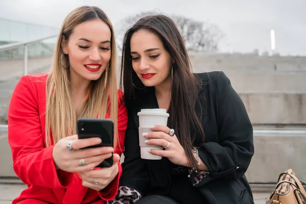 Retrato Dois Jovens Amigos Usando Seu Telefone Celular Enquanto Estão — Fotografia de Stock