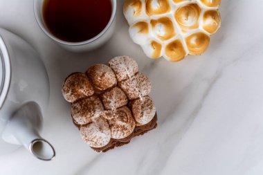 Lezzetli mini çikolatalı keke ve bir fincan çayla limonlu pastaya yakın çekim.