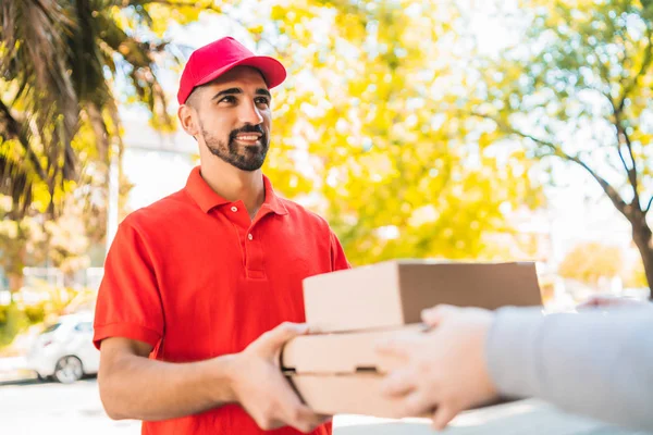 Portrait of a delivery man carrying packages while making home delivery to his customer. Delivery and shipping concept.
