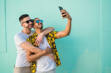 Mutlu eşcinsel çiftin portresi. Birlikte zaman geçirip cep telefonuyla selfie çekiyorlar. Lgbt ve Aşk Konsepti.
