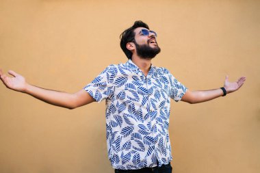 Genç yakışıklı adamın portresi yazdan zevk alıyor ve sarı arka planda yaz kıyafetleri giyiyor.. 