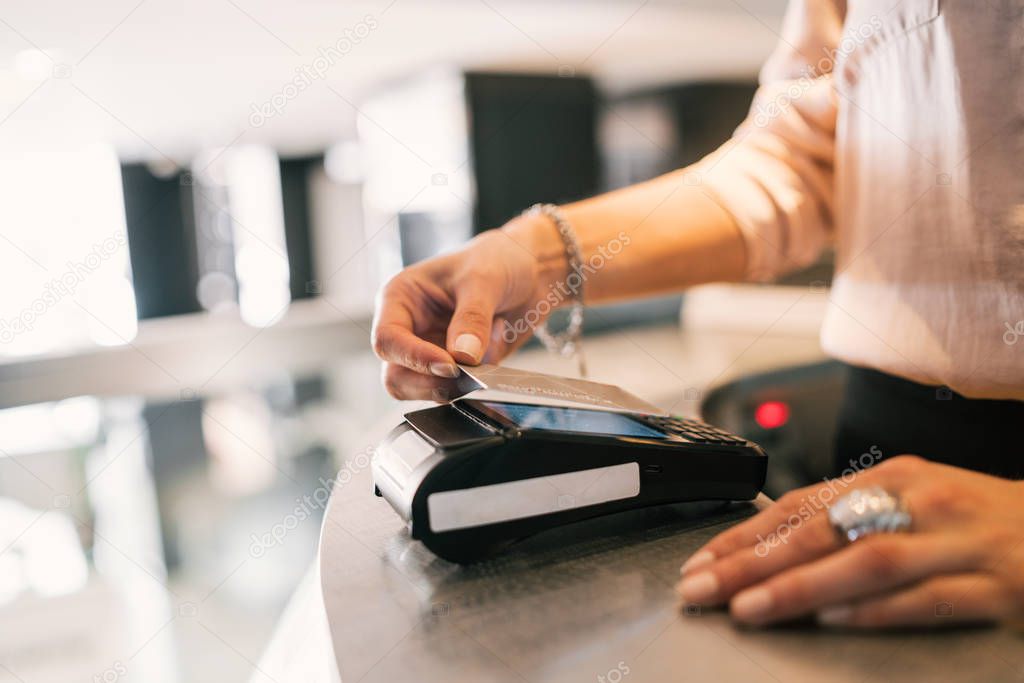 Close up of guest makes card payment at check-in at reception front desk. Travel concept.