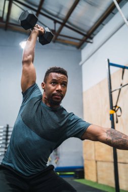 Spor salonunda dambılla egzersiz yapan genç sporcunun portresi. Crossfit, spor ve sağlıklı yaşam tarzı konsepti.
