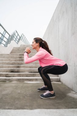 Gri duvara karşı egzersiz yapan atletik bir kadının portresi. Spor ve sağlıklı yaşam tarzı kavramı.