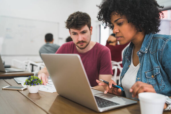 Young creative designers working in a project and discussing new order development on workplace. Business concept.