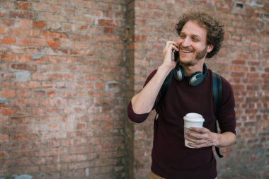 Sokakta yürürken telefonla konuşan genç bir adamın portresi. İletişim ve şehir kavramı.