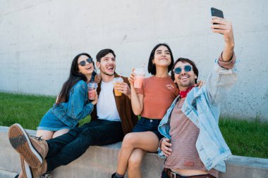 Birlikte eğlenen ve cep telefonuyla selfie çekerken eğlenen bir grup arkadaşın portresi. Yaşam tarzı ve arkadaşlık kavramı.
