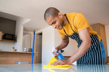 Evdeki masadaki lekeleri temizleyen genç latin adama yakın durun. Oda servisi ve temizlik konsepti.