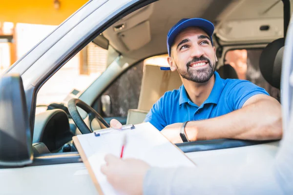 Müşteri panoya imza atarken minibüsteki bir teslimatçının portresi. Teslimat ve nakliye konsepti.